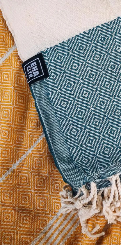 "Green and white patterned cotton label with fringe, resting on a yellow geometric design fabric."
