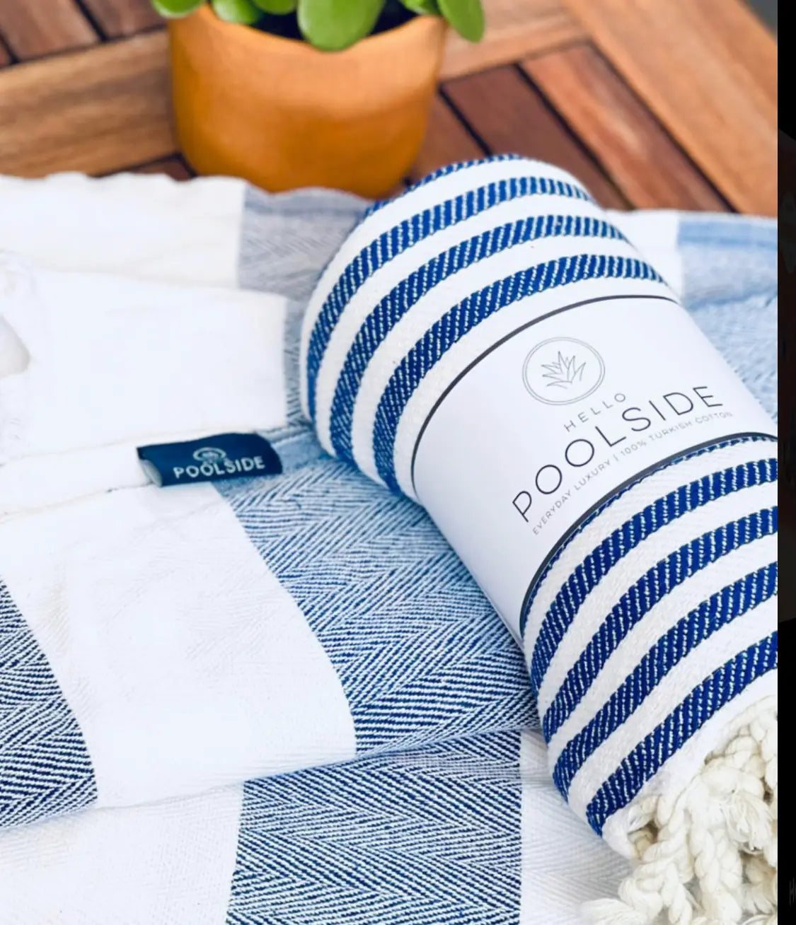 "White and blue striped cotton label with tassels, resting on a textured light blue and white blanket."