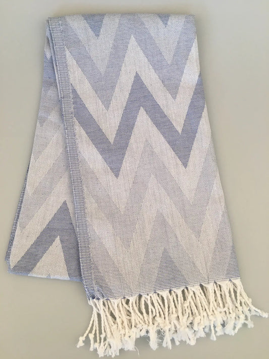 "Light blue and white jacquard peshtemal with chevron pattern and fringed edges, laid flat on a neutral background."
