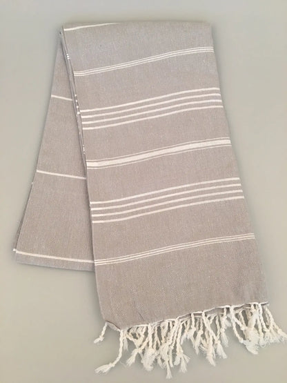 "Gray Turkish towel with white stripes and fringed edges, folded neatly on a light background."