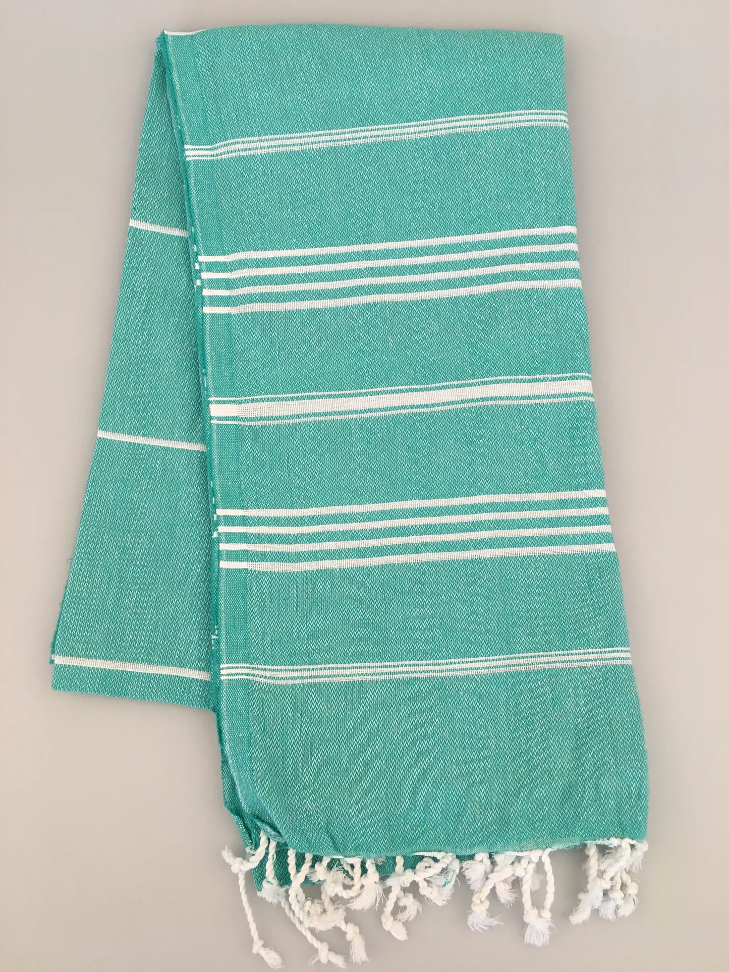 Aphrodisias Sultan Turkish towel in turquoise with white stripes and fringed edges, displayed flat on a light background.