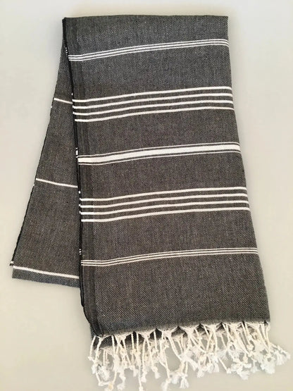 Gray Turkish towel with white stripes and fringed edges, neatly folded on a light background.