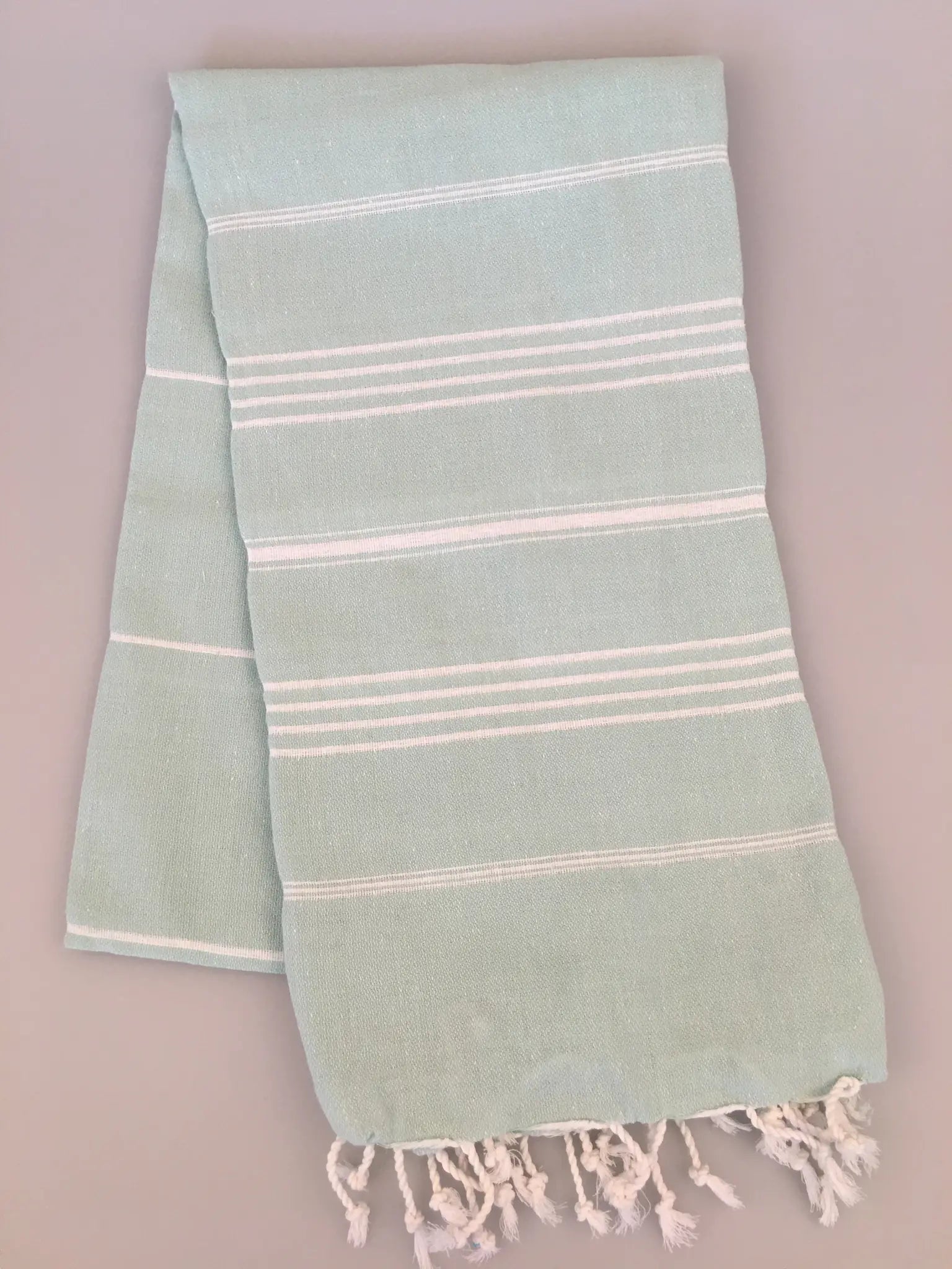 Aphrodisias Sultan Turkish Towel in light green with white stripes and fringed edges, laid flat on a neutral background.