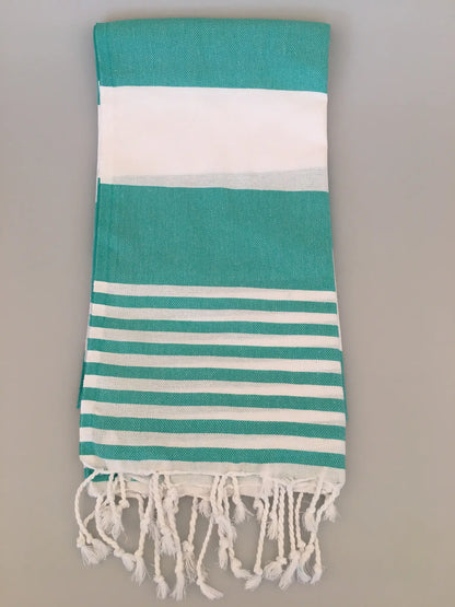 "Turquoise and white striped Turkish towel with fringed edges, folded view on a light background."