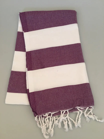 "Pinara Turkish Towel Peshtamal in deep purple and white stripes, folded with fringed edges, top view."