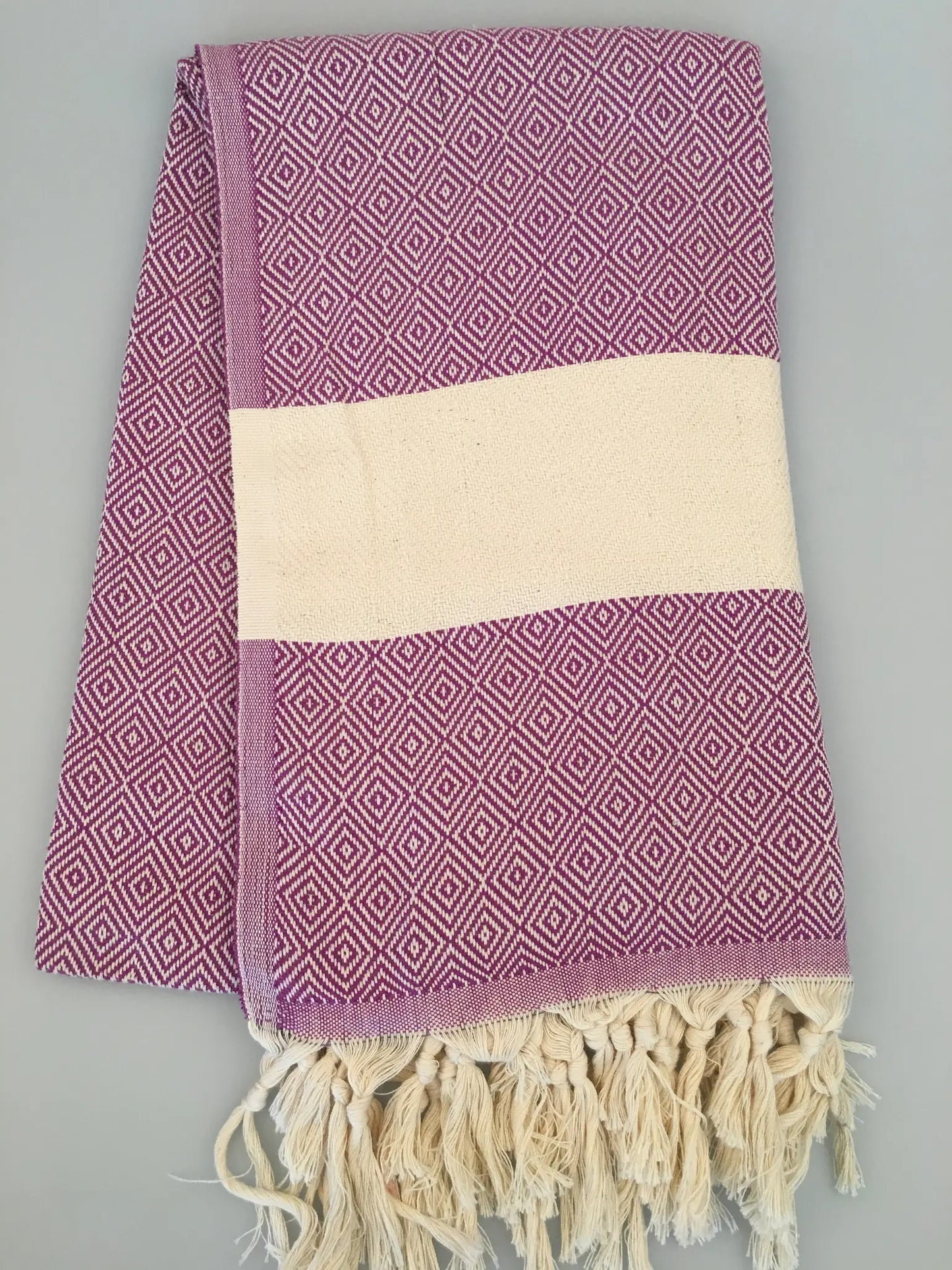 "Lycia Myra Turkish towel in purple with diamond pattern, cream center band, and fringed edges, laid flat"