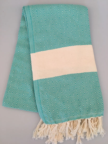 Aqua blue Turkish towel with diamond pattern, featuring a beige band and fringed edges, laid flat.