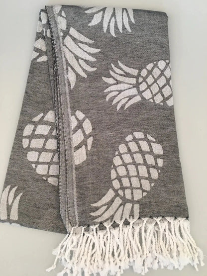 Gray Turkish towel with white pineapple jacquard pattern and fringed ends, laid flat on a light background.