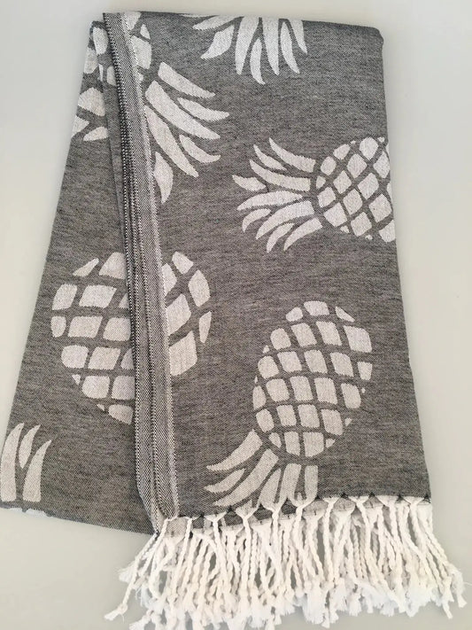 Gray Turkish towel with white pineapple jacquard pattern and fringed ends, laid flat on a light background.