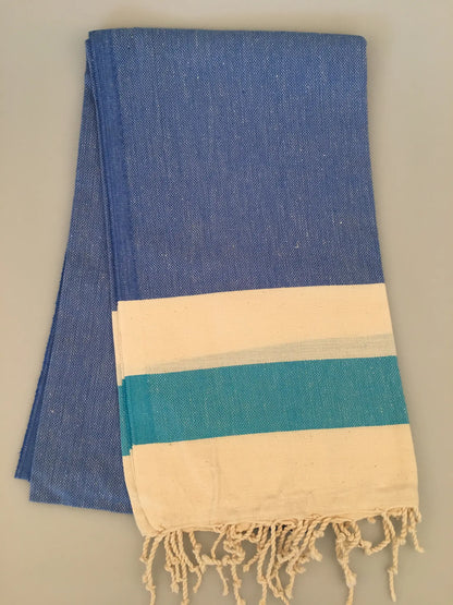 "Blue and white striped Turkish towel with fringed edges, folded neatly on a light gray background."
