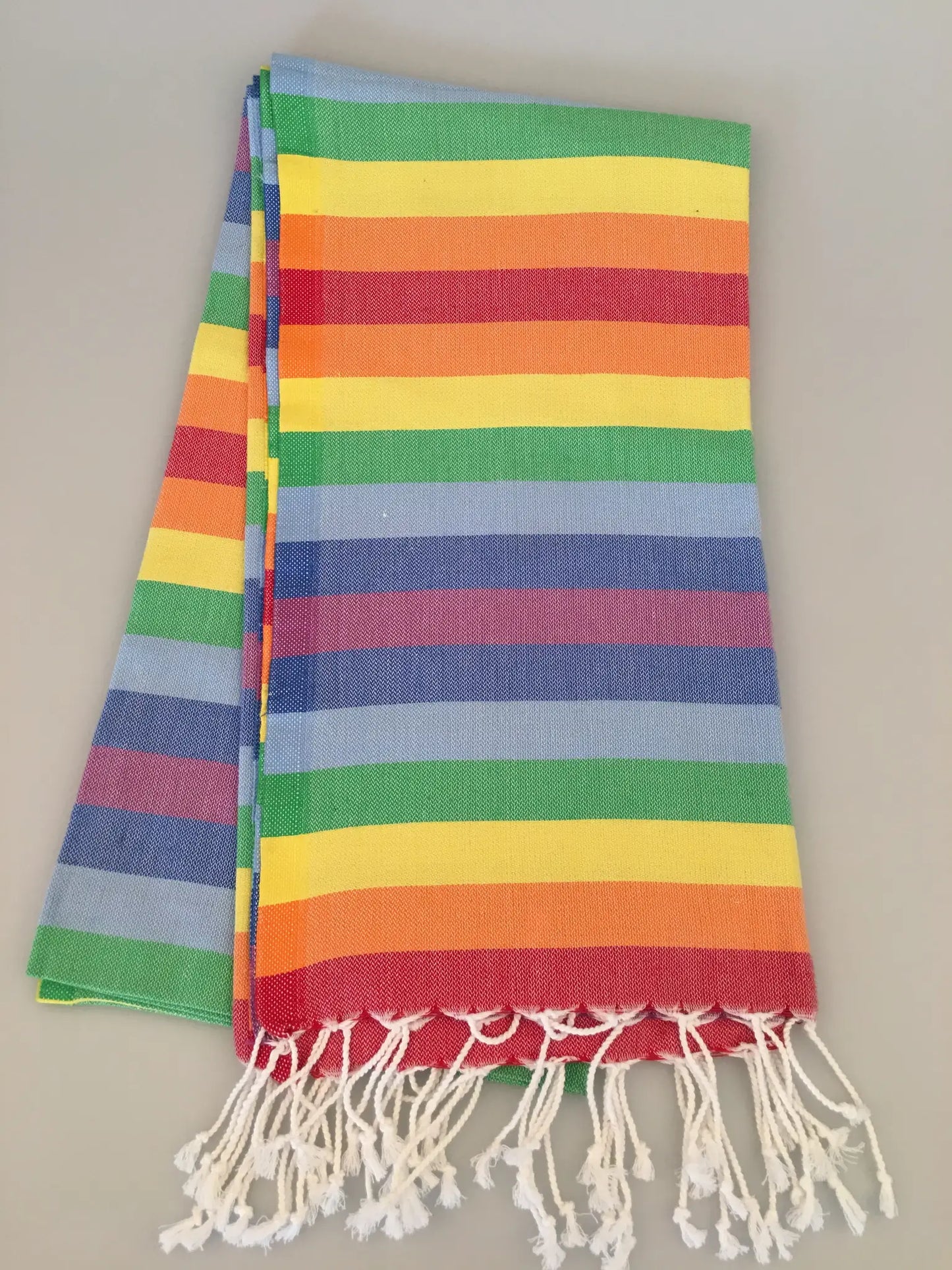 Colorful Cadyanda Turkish towel peshtemal with horizontal stripes in red, yellow, green, blue, and white fringes.