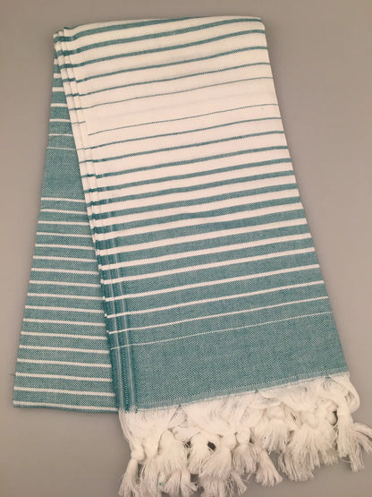 Aqua and white striped Turkish towel with fringed edges, neatly folded on a gray background.