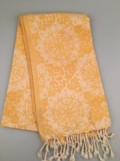 "Yellow jacquard peshtemal with a circular pattern, fringed edges, displayed folded against a light background."