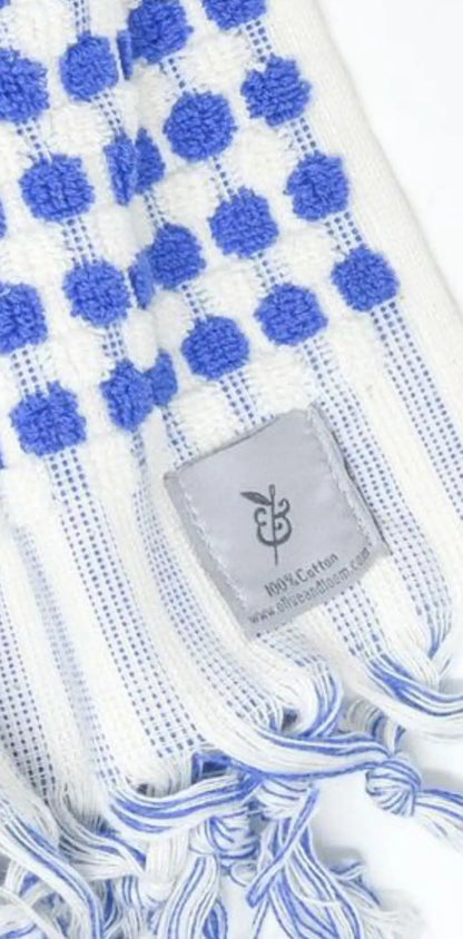 "White cotton label with blue polka dots and fringed edges, featuring a gray stitched label at the bottom."