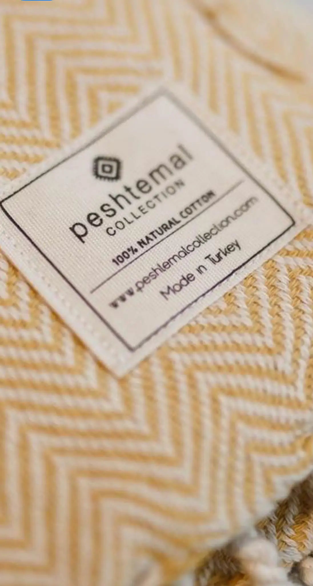 Woven cotton label with a herringbone pattern, featuring a white background and black text, corner view.
