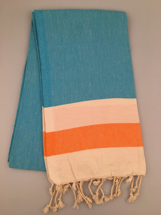 Blue Turkish towel peshtemal with orange and cream stripes, featuring fringed edges, laid flat on a neutral background.