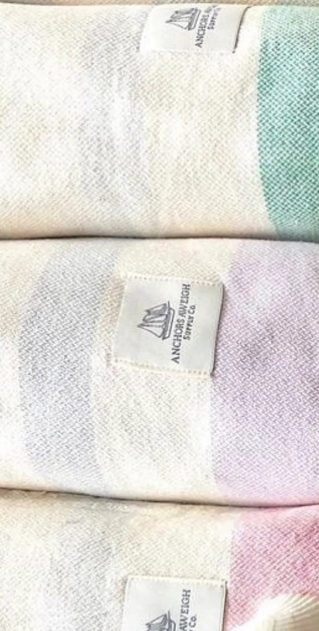 "Stacked cotton labels in pastel colors with a small logo tag, featuring green, pink, and white stripes."