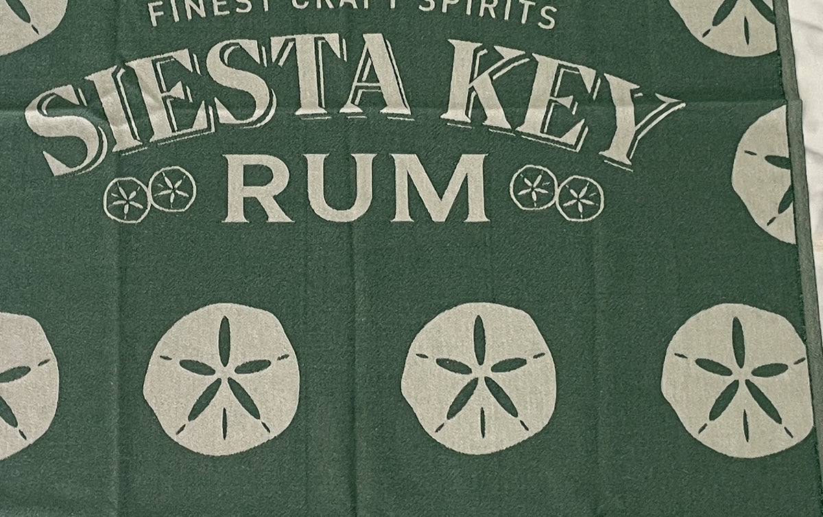 Jacquard-woven Turkish towel with Siesta Key Rum wordmark and sand dollar motif, detail crop